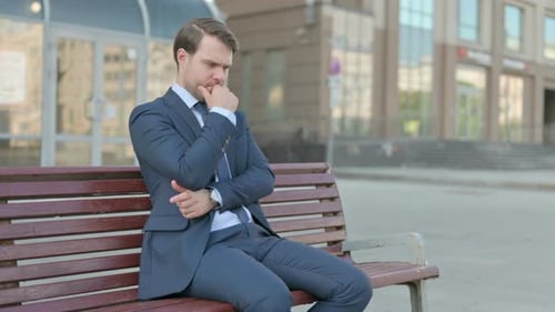 Pensive Businessman Thinking while Sitting Outdoor on Bench