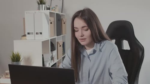 Girl in a Modern Office Working on a Laptop