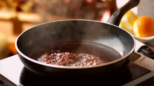 Dunkle Flüssigkeit kocht auf einer Pfanne.