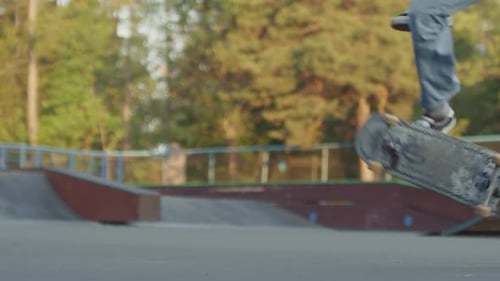 Slowmo d'un adolescent méconnaissable faisant du kickflip sur une planche à roulettes