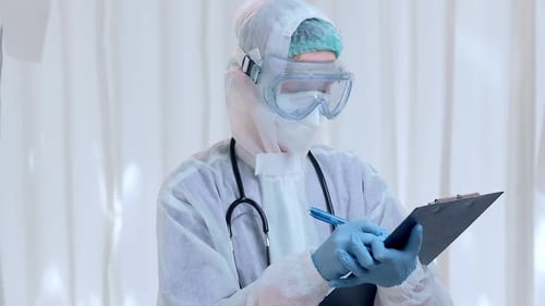 Medical Worker Writes on Clipboard in Protective Suit