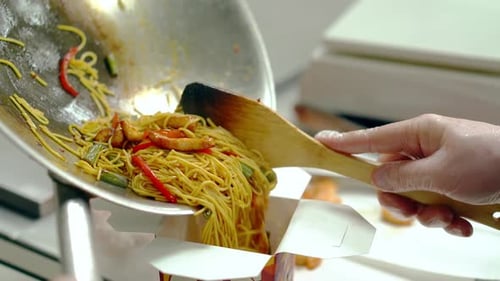 Pouring Asian Inspired Noodles into Take Out Container