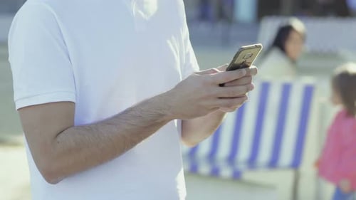 Man Uses Cellphone Outdoors in Urban Setting