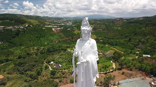 Aerial of White Lady Buddha Statue with Mountains, Countryside Village and Farm