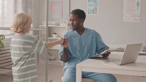 Friendly Doctor Talking with Young Patient in Clinic