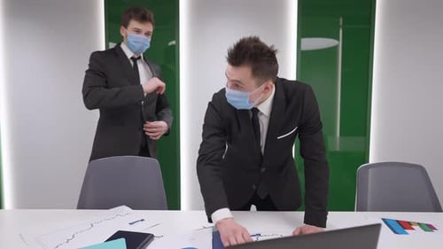 Two Positive Caucasian Men in Coronavirus Face Masks Greeting in Office Indoors