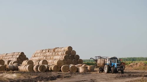 Tractor Loading Hay Bales in a Field
