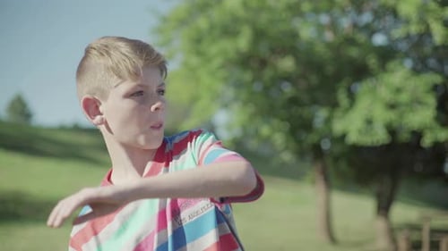 Boy Standing in a Grassy Field on Sunny Day