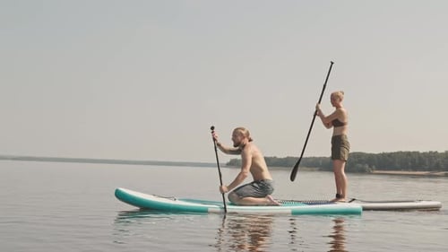 Man and Woman Paddle Boarding on Serene Lake