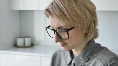 Woman with Glasses Focused on Screen Indoors
