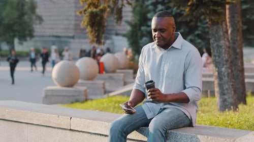 Man Relaxing with Coffee and Phone in City Park