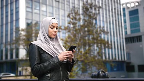 Portrait of Young Stylish Muslim Business Woman in Hijab Using Phone in Business Area
