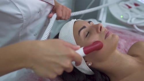 Woman Receiving Red Light Facial Treatment in Clinic