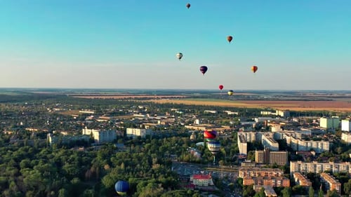 Multicolored balloons fly over trees. Nice top view of the park, forest covered with greenery.