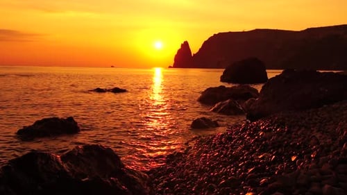 Ein roter brennender Sonnenuntergang mit der Silhouette einer Klippe über dem Meer