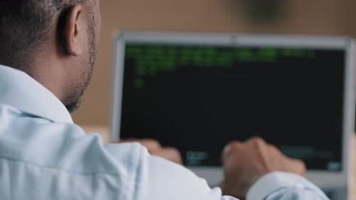 Back Rear View of Unrecognizable African Young Man Working at Computer IT Programmer Engineer
