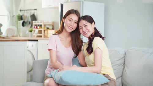 Two Young Women Smiling and Chatting on Sofa