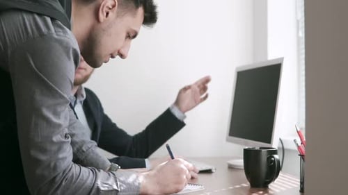 Two Concerned Workers in a Meeting in an Office Looking at Each Other with Serious Expressions