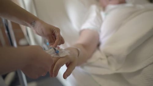 A nurse injecting medicine to an old lady via scalp vein needle