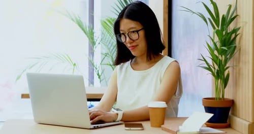 Woman Types at Laptop in Bright Workplace
