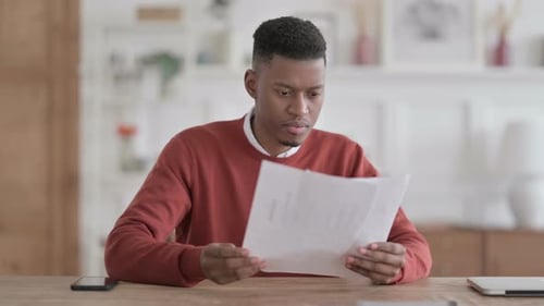 African Man Reacting to Loss on Documents in Office