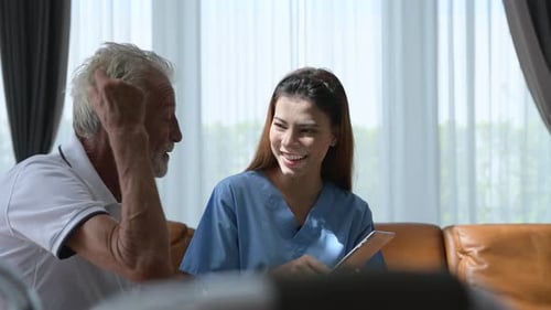 Friendly Caregiver Talks with Elderly Man at Home