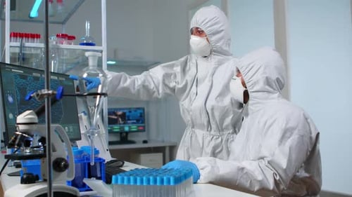 Equipo de científicos en traje de protección discutiendo frente a la PC
