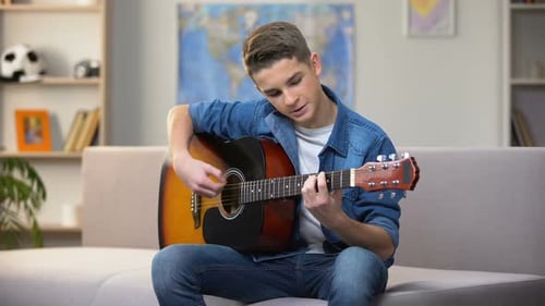 Teenager Plays Guitar on Couch at Home