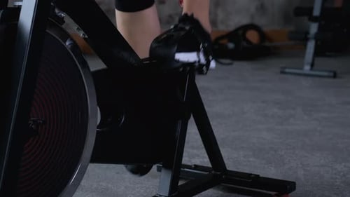 Portrait of attractive young woman in gym on stationary bike. Exercise bike cardio workout