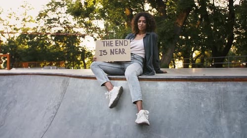 Afroamerican Female is Holding Cardboard Tablet with Inscription the End is Near While Posing