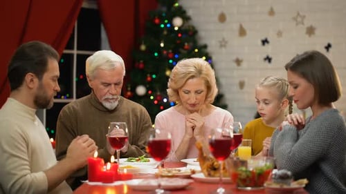 Family Saying Grace Before Christmas Meal Together