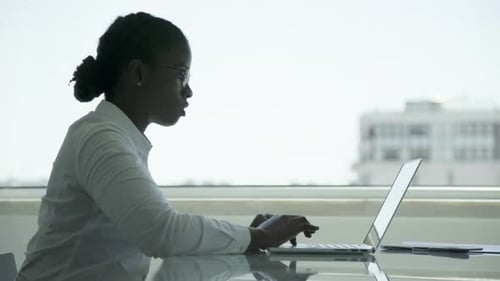 Woman Typing on Laptop in Bright Office