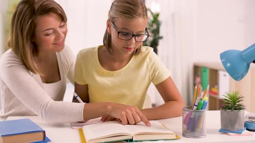 Adult Woman Tutoring Child at Desk Indoors