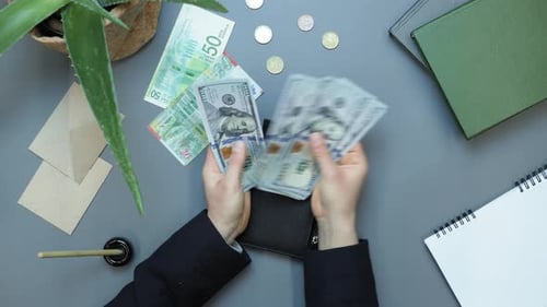 Hands put cash money in wallet against work desk table
