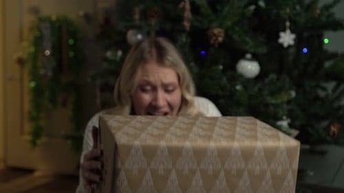 Woman Laughing while Opening Christmas Gift