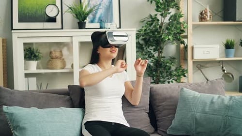 Young Woman Using VR Headset on Sofa