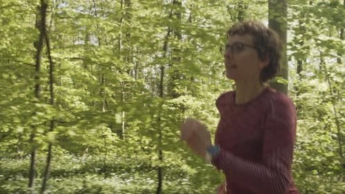 Backward Tracking Shot of a Woman Going for an Early Run in the Forest