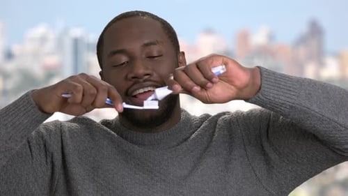 Afro-american Guy Putting on Toothpaste on Toothbrush.