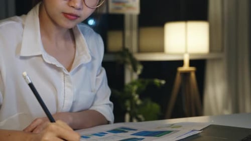 Woman Works Late at Night with Financial Documents