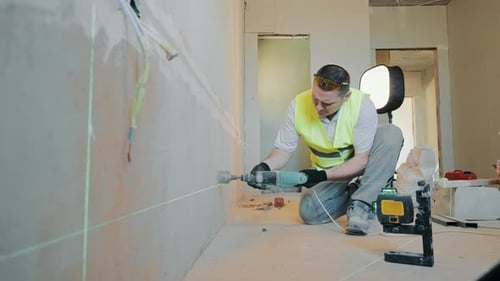 Vue du dessus Un ouvrier du bâtiment perce un trou dans le mur sous la douille