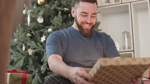 Man Smiling While Opening Christmas Present
