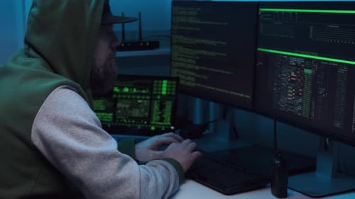 Man Typing at Computer Surrounded by Screens