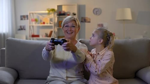 Grandmother and Grandchild Playing Video Game on Couch