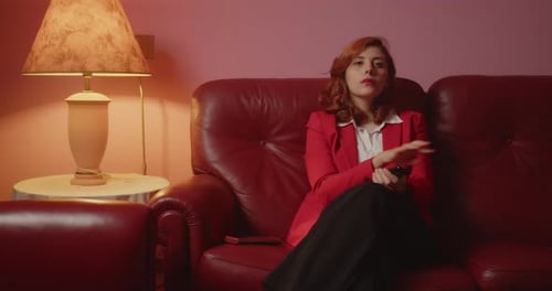 Young Woman Changing Channels on Red Leather Couch