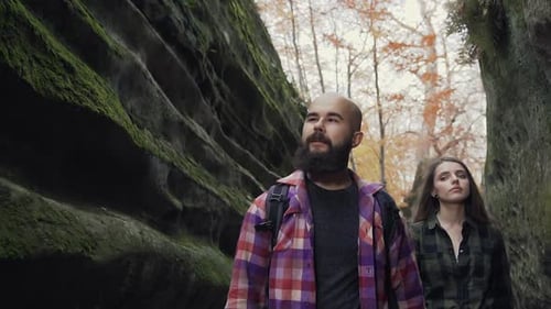 Woman and a Man with a Beard Walking Along the Path of a Pedestrian Path Between the Stones