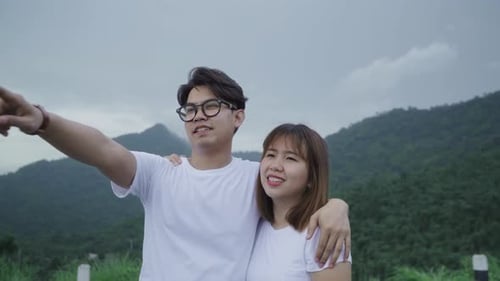 backpacker couple on hiking adventure feeling freedom walking in forest near lake in rainy day.