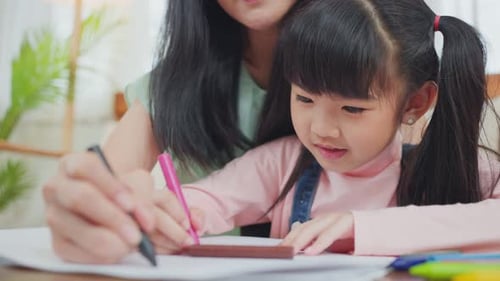 Child Drawing With Mother At Home Indoors