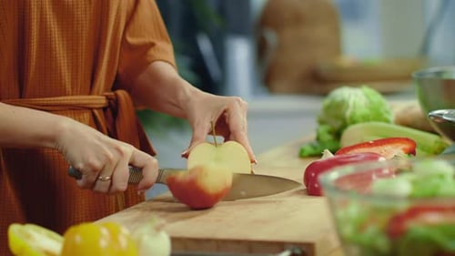 Woman Prepares Salad Slicing Apple in Kitchen