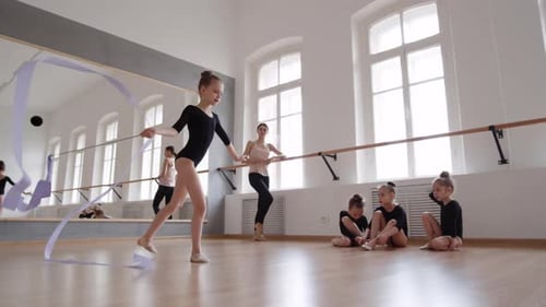 Girl Practices Ribbon Gymnastics in Bright Studio
