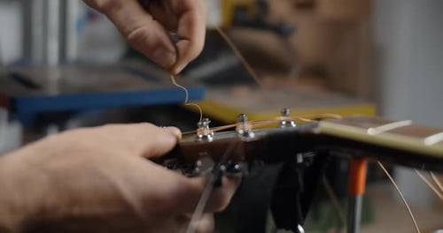 Craftsman Replacing Guitar Strings in his Workshop